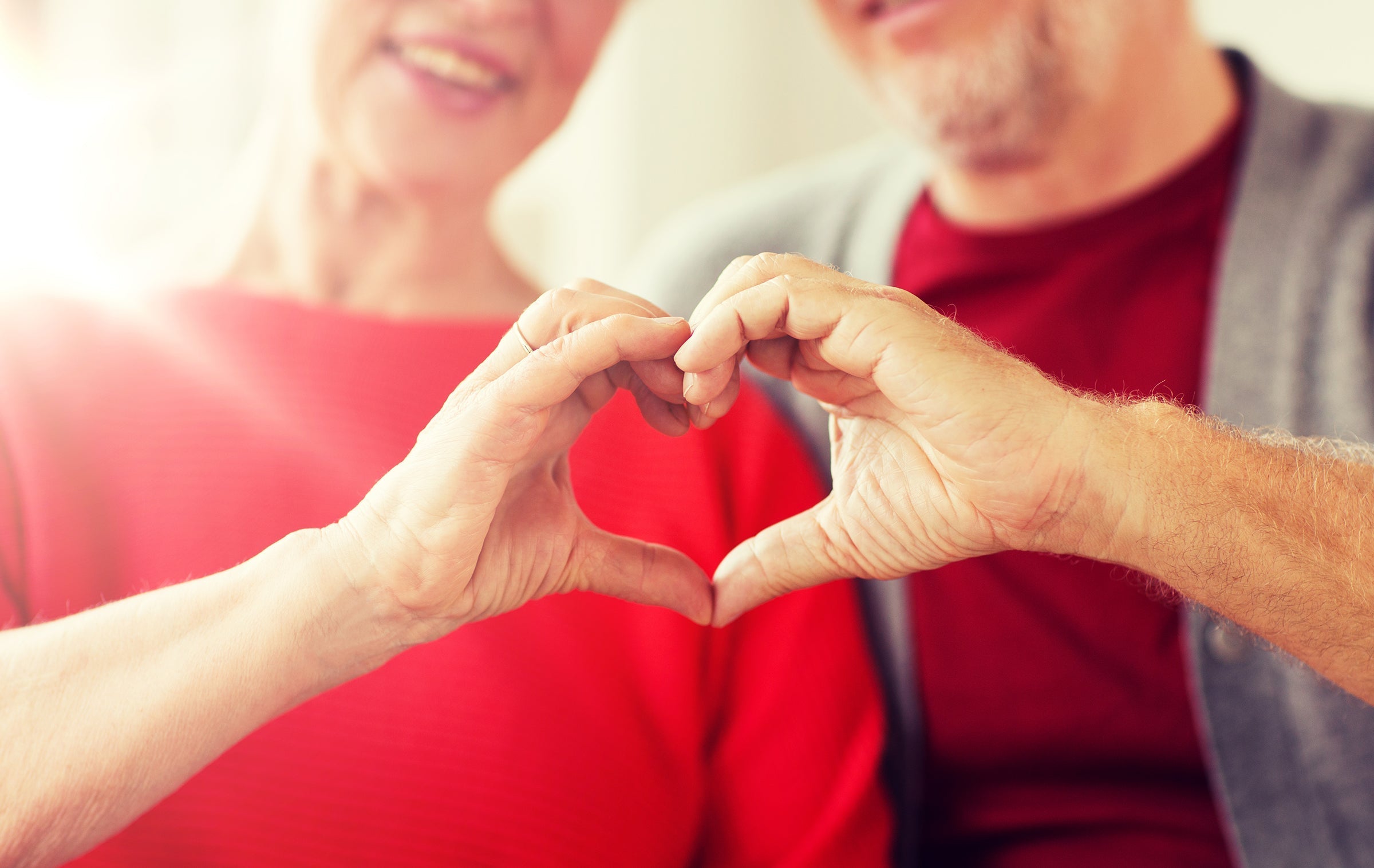 relationships, love and old people concept - close up of senior couple showing hand heart gesture