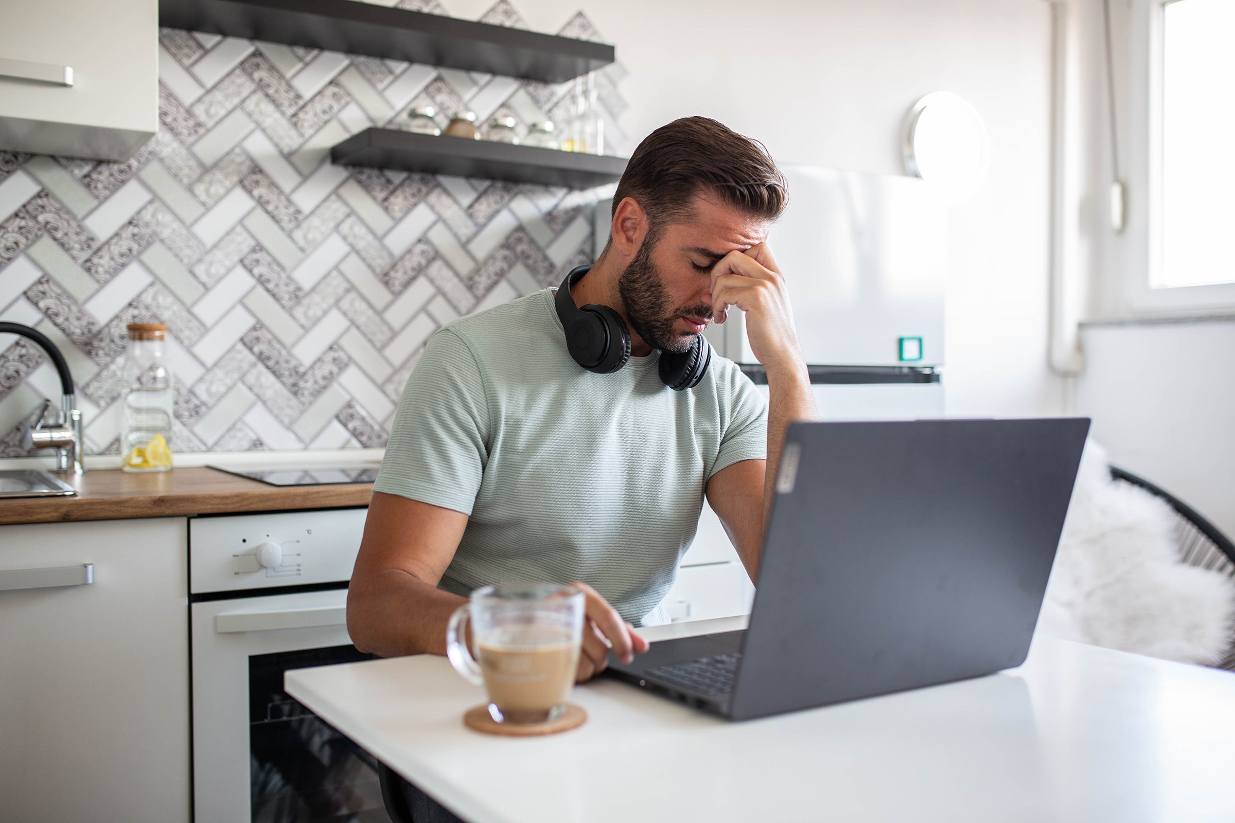 Stressed business man working from home on laptop looking woried and tired