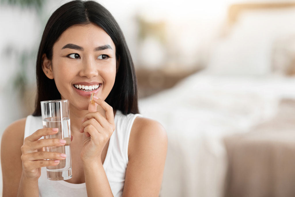 woman taking capsule with water