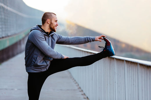 Athletic runner doing stretching exercise, preparing for morning workout in the park