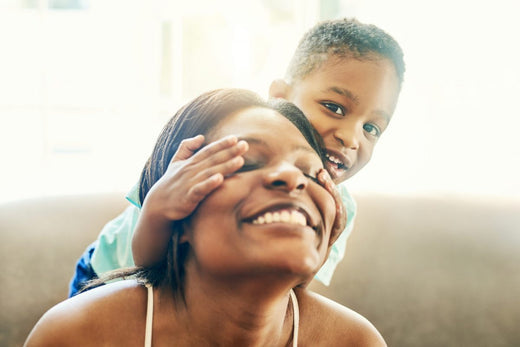 Shot of a little boy covering his mother's eye while playing together at home