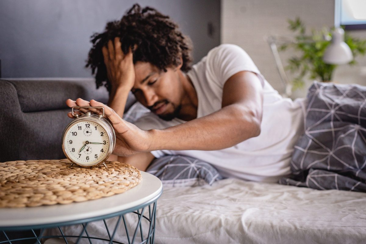 A man wakes up in bed under stress