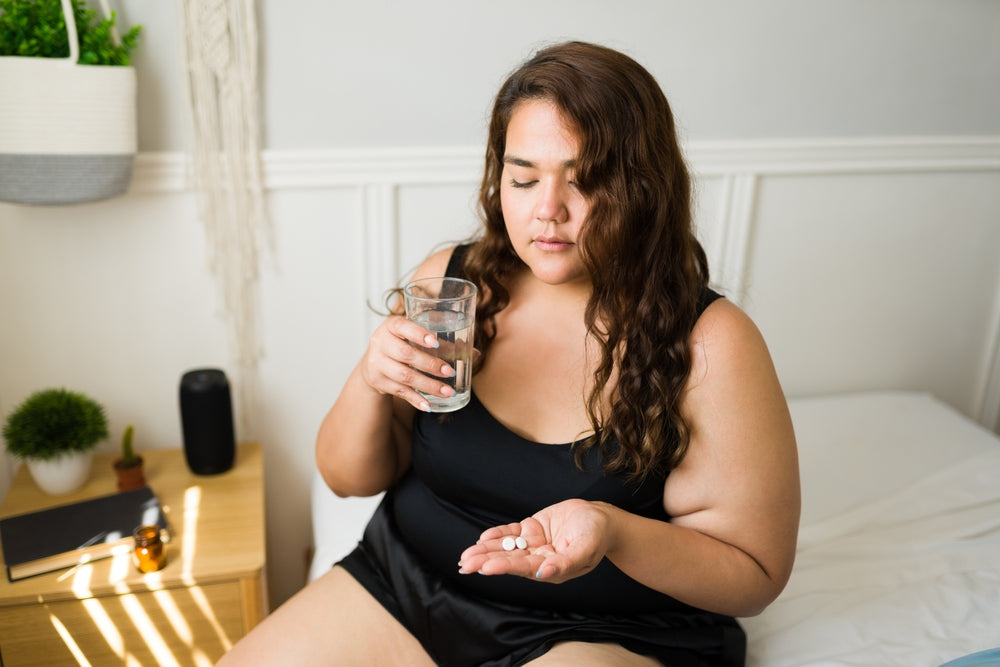 woman drinking water while taking vitamins
