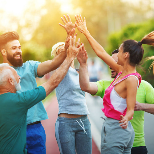 A diverse group of friends high five each other on a residential road