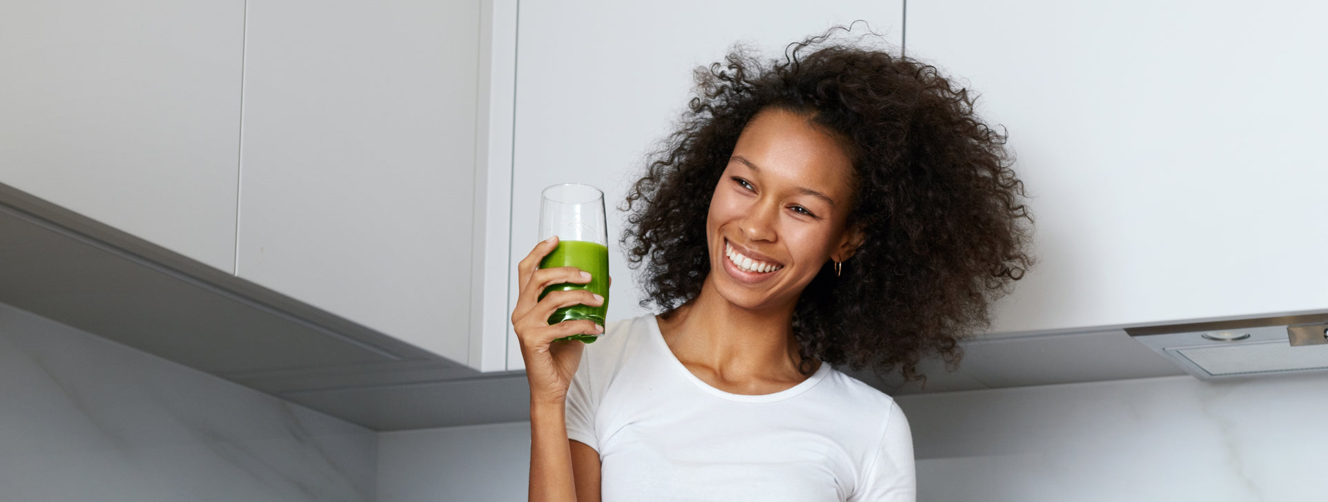 An African American woman looks at her healthy looking green juice