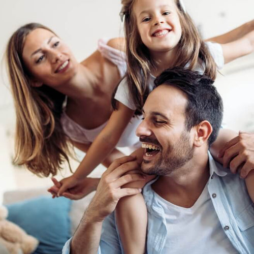 A family of three plays in a living room setting