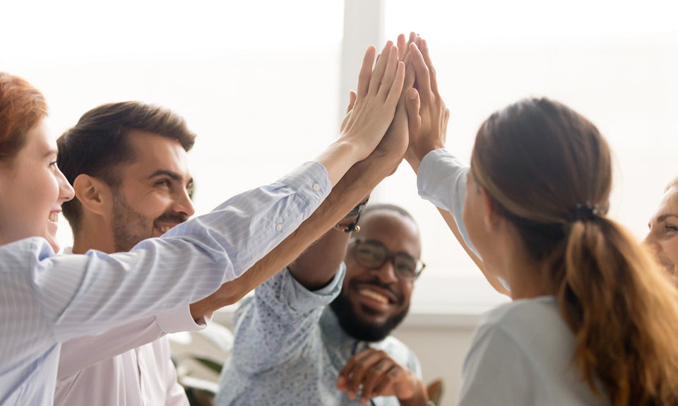 A multiracial team high-fives in an office setting