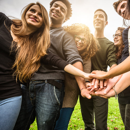 A closeup scene of a group of friends holding hands and smling