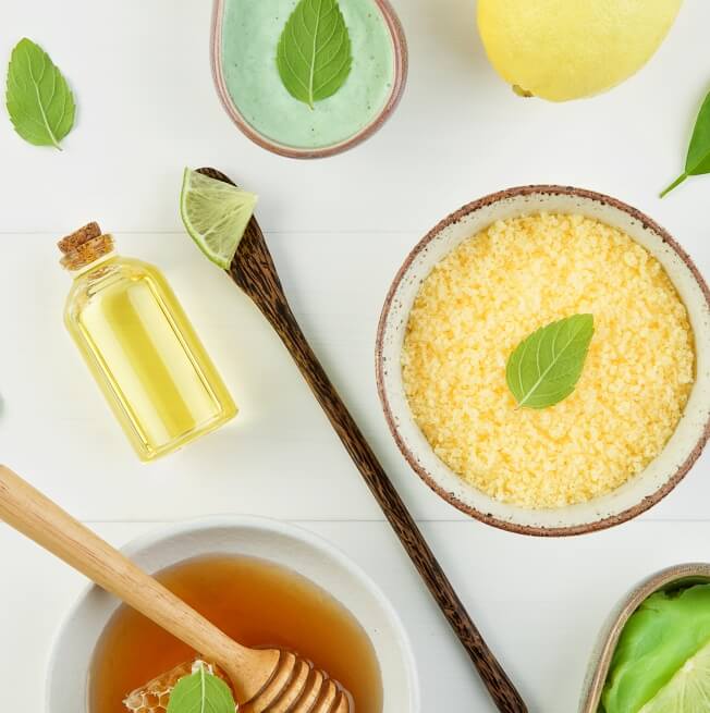 An arrangement of herbs, honey, and oils on a white background