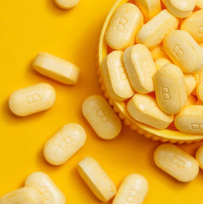 A closeup photo of yellow pills in a yellow basket on a yellow background